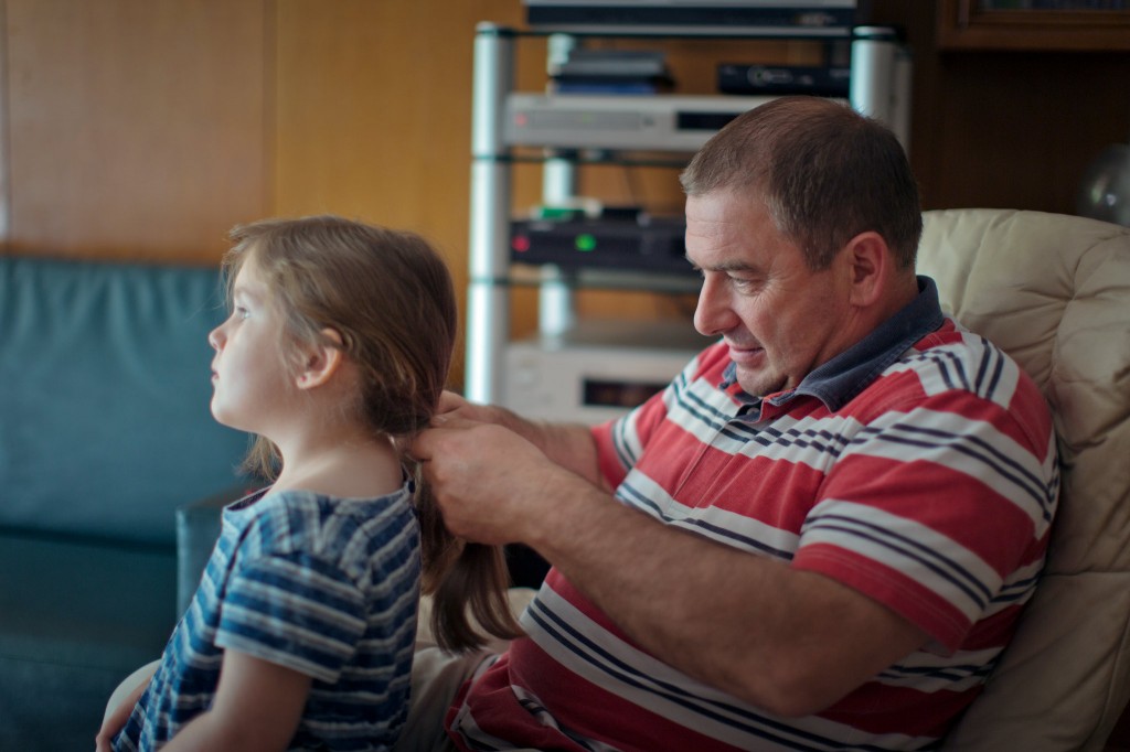 Older man braiding young girls's hair