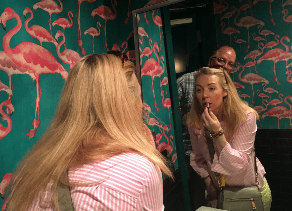 woman applying lipstick in bathroom mirror