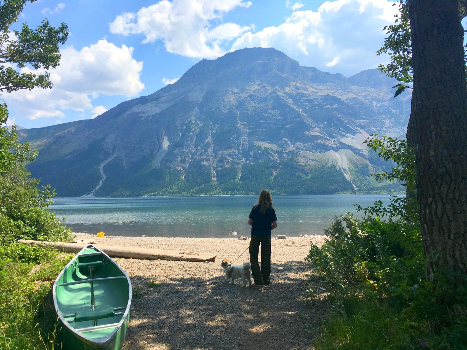girl walking dog by mountain lake
